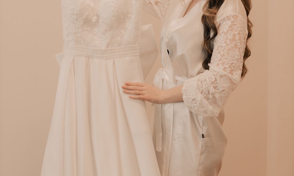 A bride admiring a wedding gown on a hanger (stock photo)